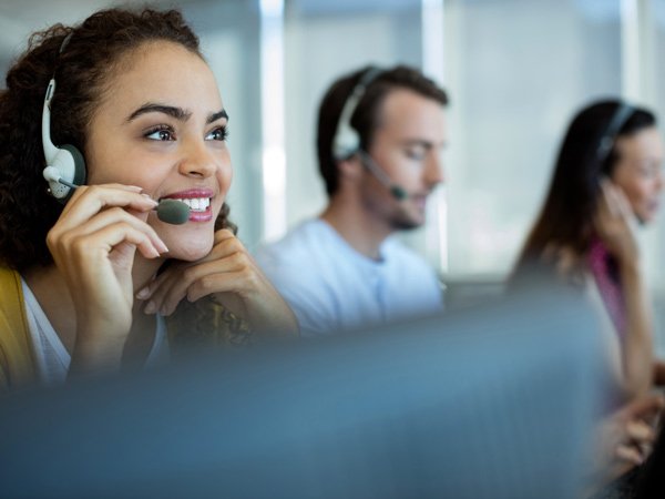 Team of people using headsets in front of computers.
